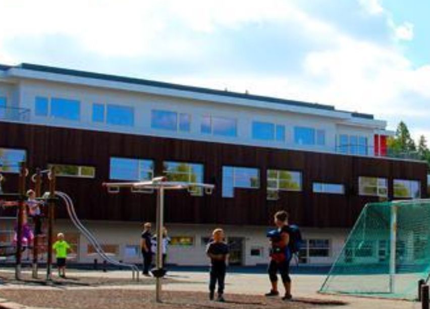 Barn leker på en lekeplass utenfor en skole.
