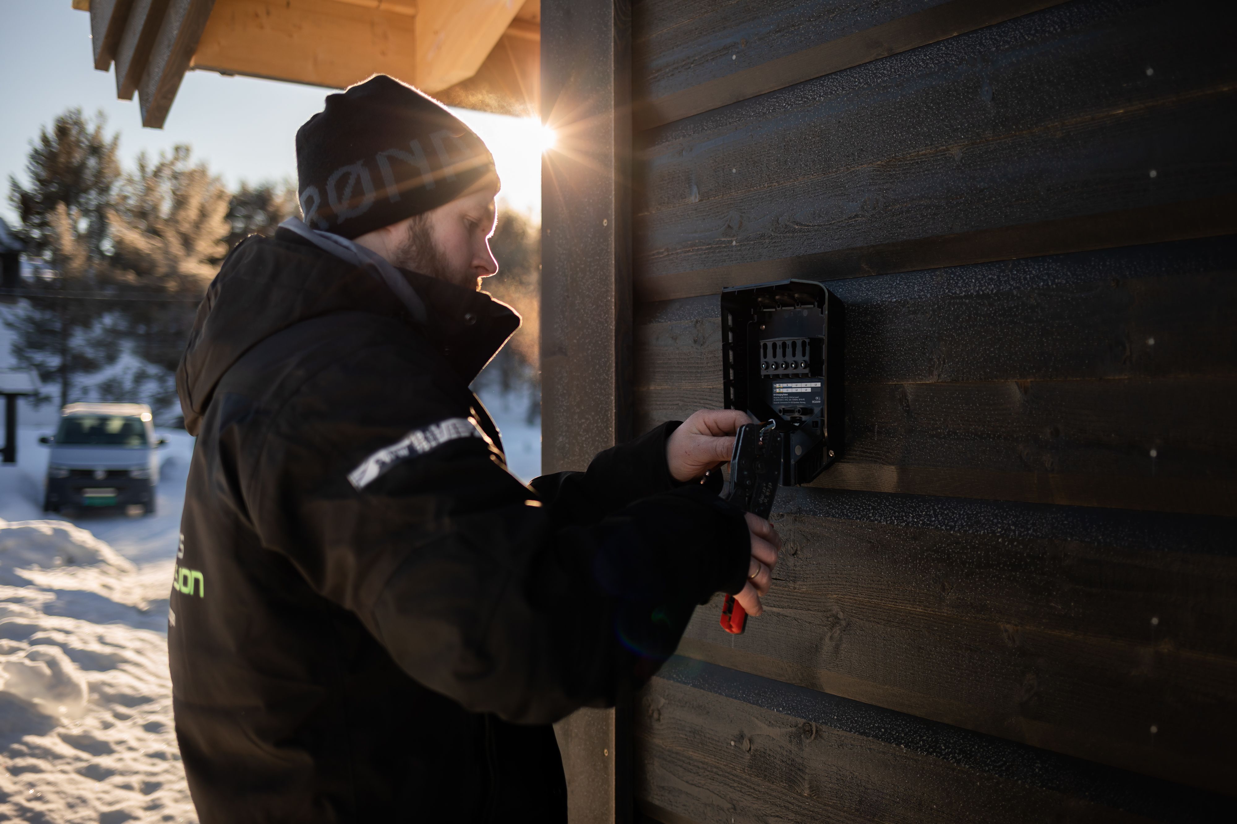 Elektriker fra Valdres Installasjon installerer en elbillader på hyttevegg i Valdres