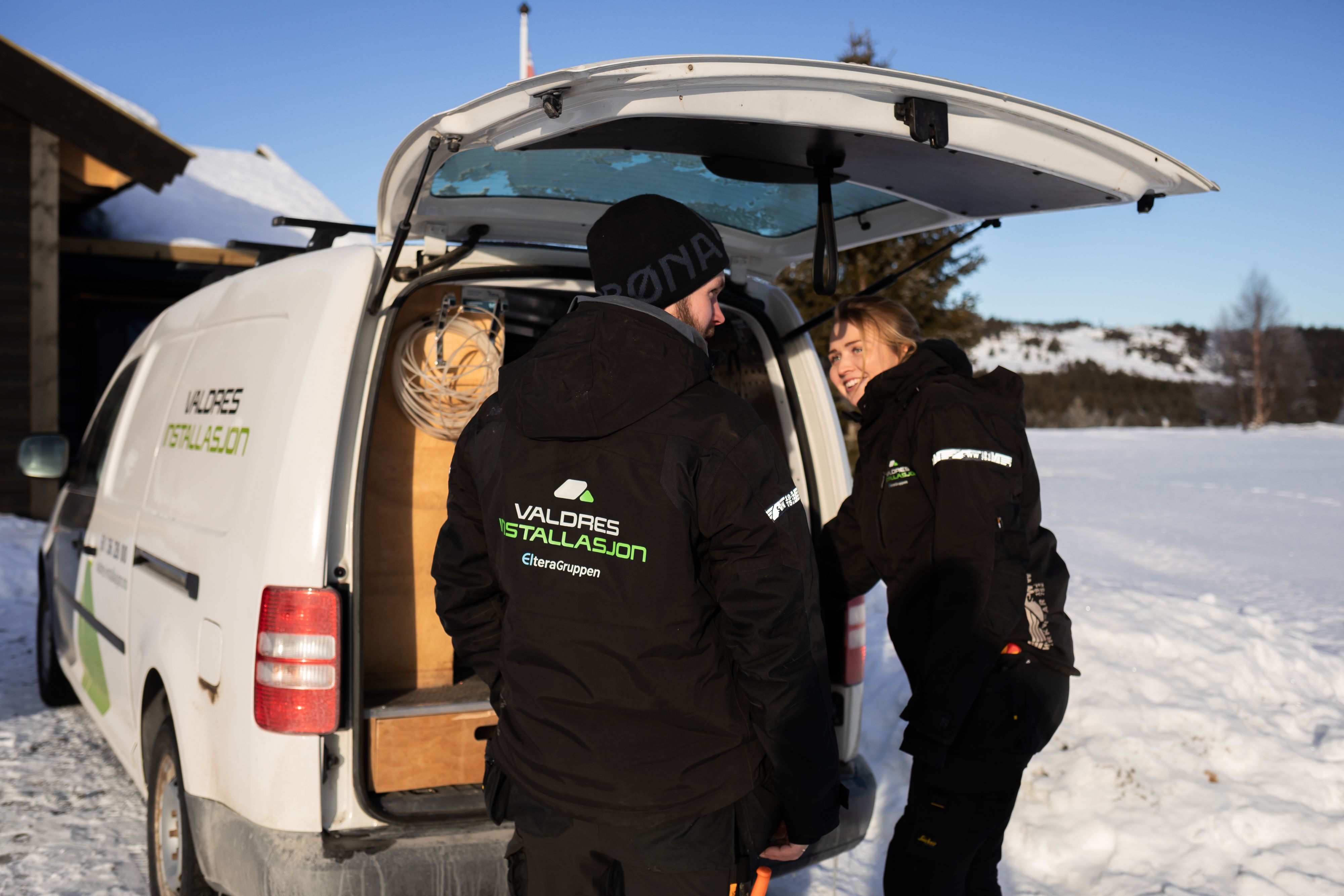 Elektrikere fra Valdres Installasjon smiler og snakker på vei til arbeid på hytte i Valdres