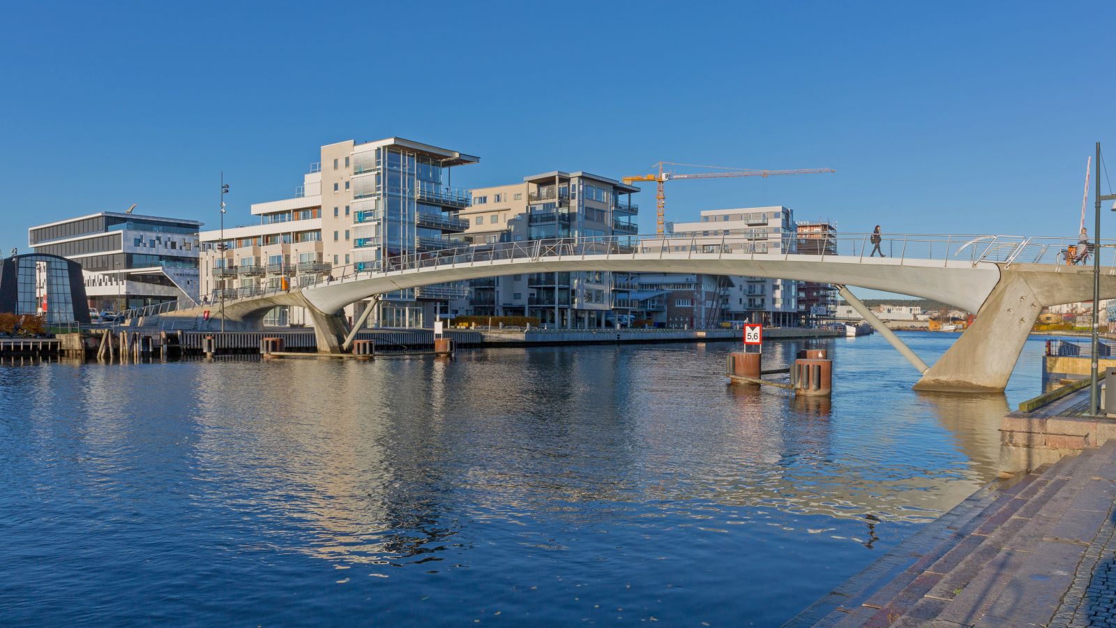 Panoramabilde av Glomma og Fredrikstad med en blanding av eldre, gult tømmerhus og moderne leilighetsbygg. En elegant, moderne gangbro krysser elven. Østfold Norge Norway