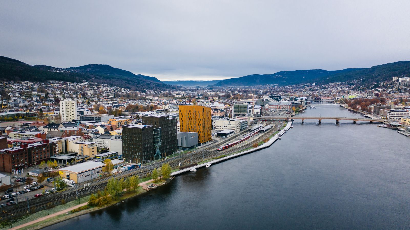 Et oversiktsbilde av Drammen by med elven, jernbanesporene og de karakteristiske moderne bygningene i forgrunnen. Buskerdu Norge Norway
