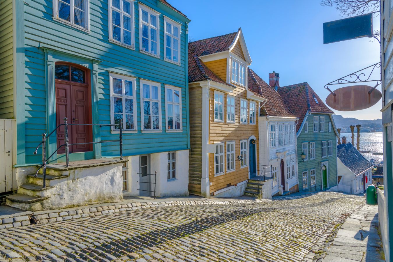 Bilde av en smal gate i Bergen med brosten og fargerike hus. 