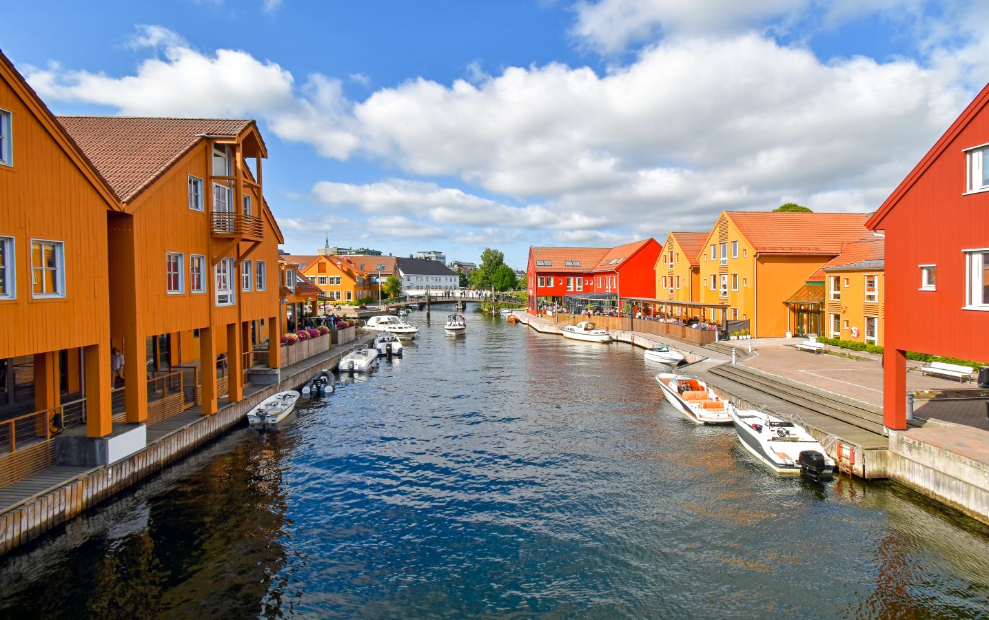 Bilde av Kristainsand fiskebrygge med båter og små hus i farger. 