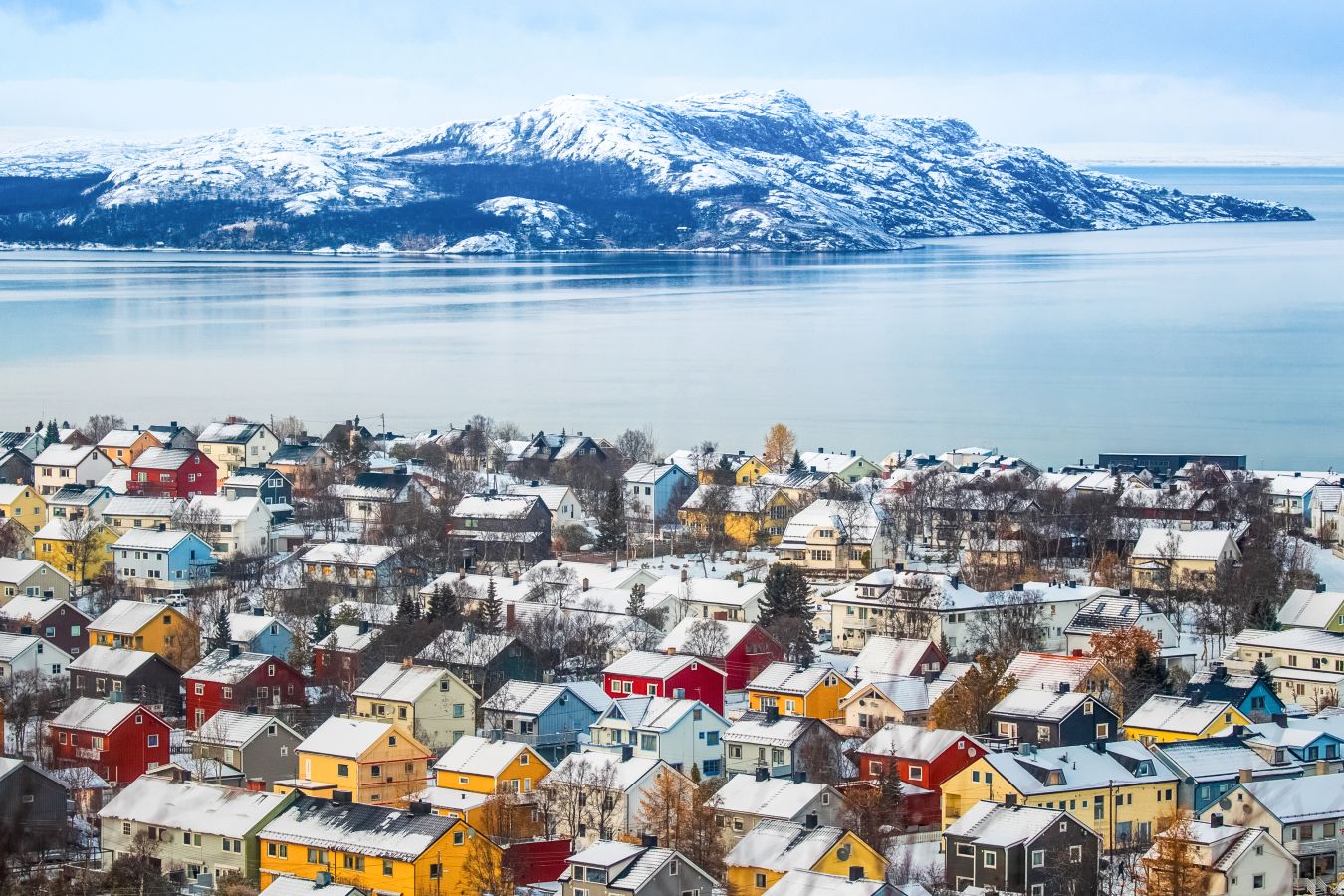 Flyfoto av Kirkenes i Finnmark med fargerike hus og sjøen.