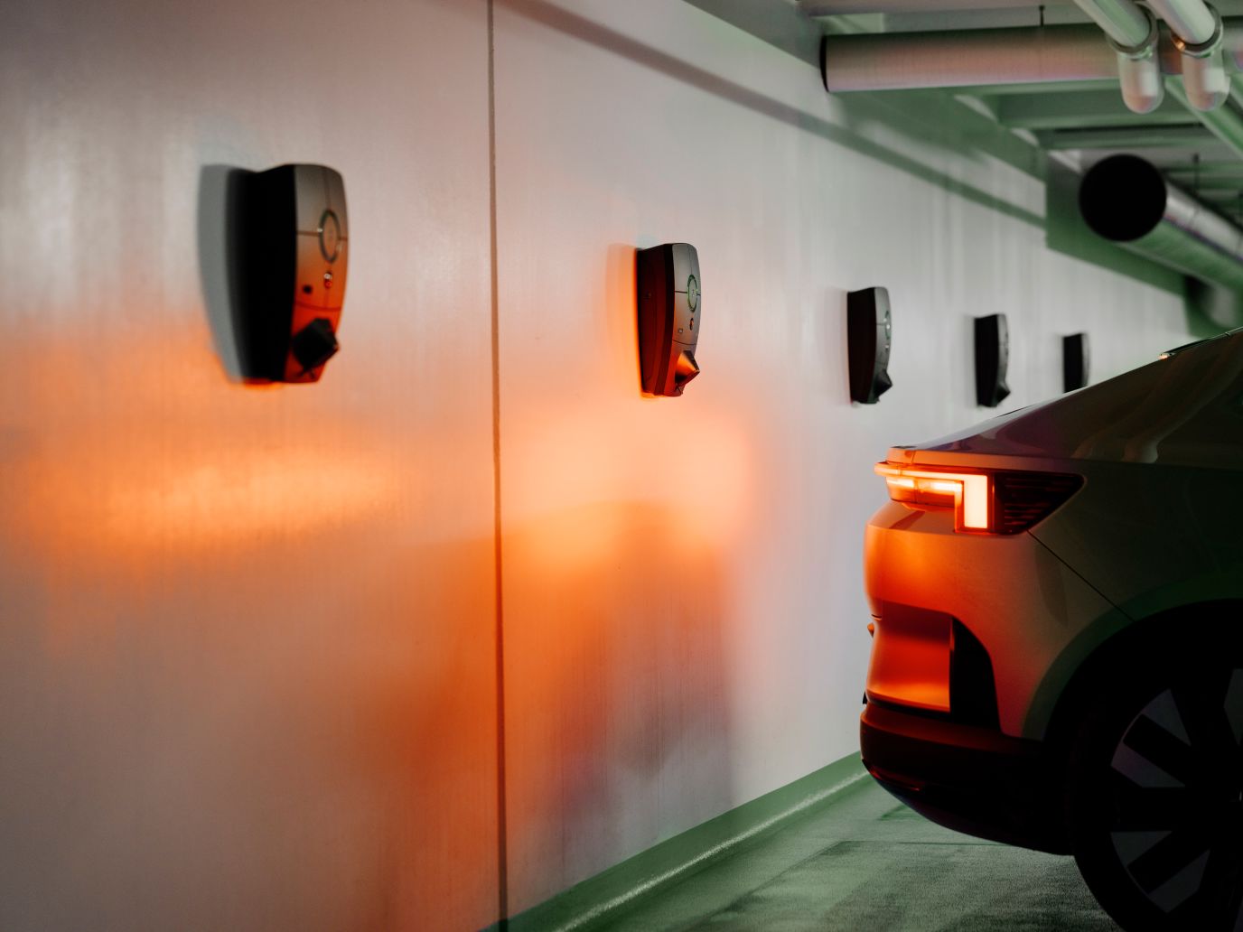 Bilde av en bil parkert i en garasje med en zaptec laderer langs veggen.