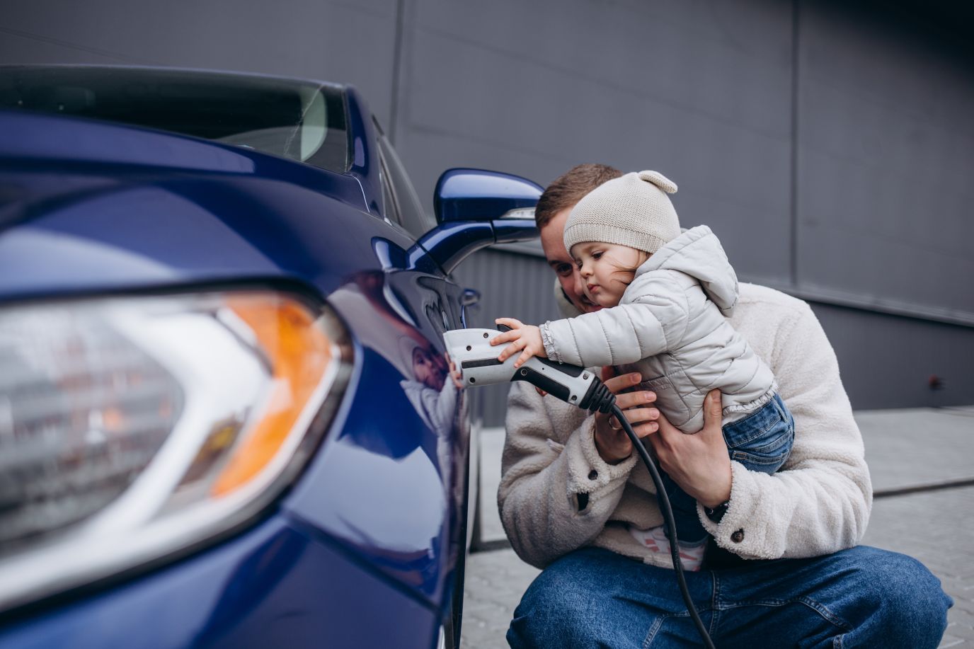 En far som lader elbilen sammen med datteren sin