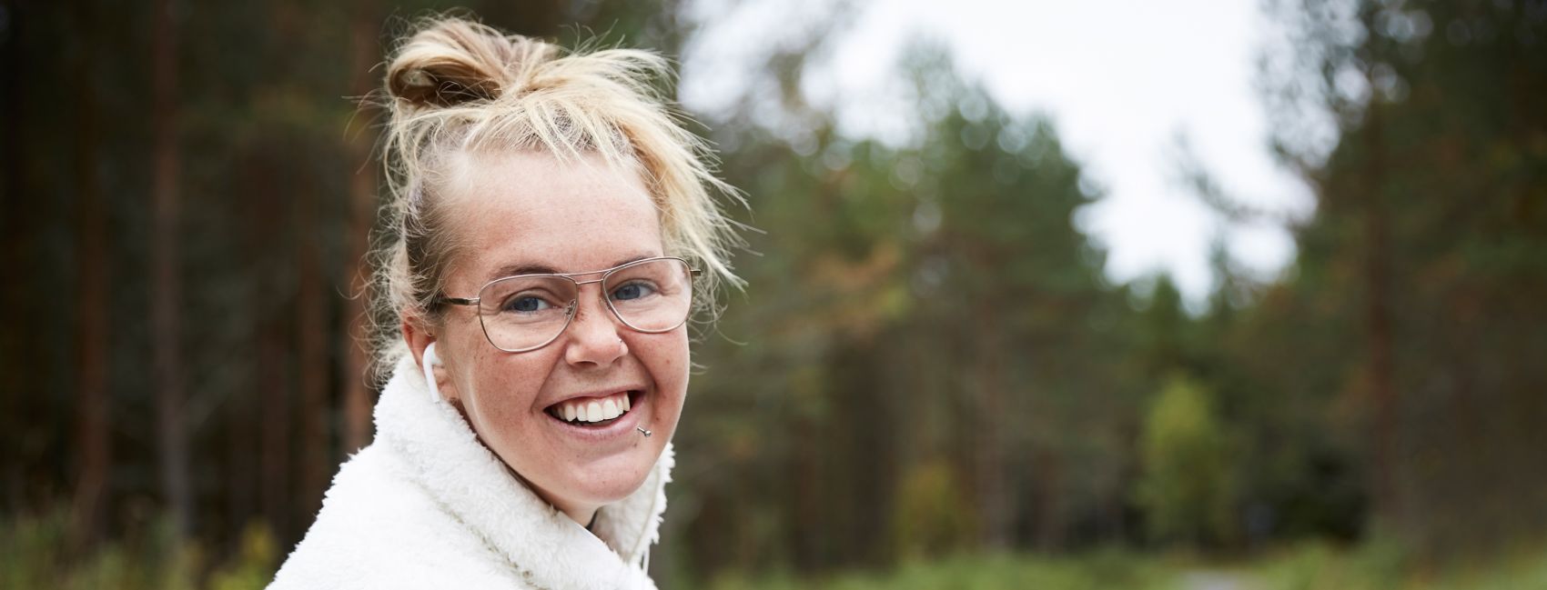 Ung kvinne i hvit genser med kule briller