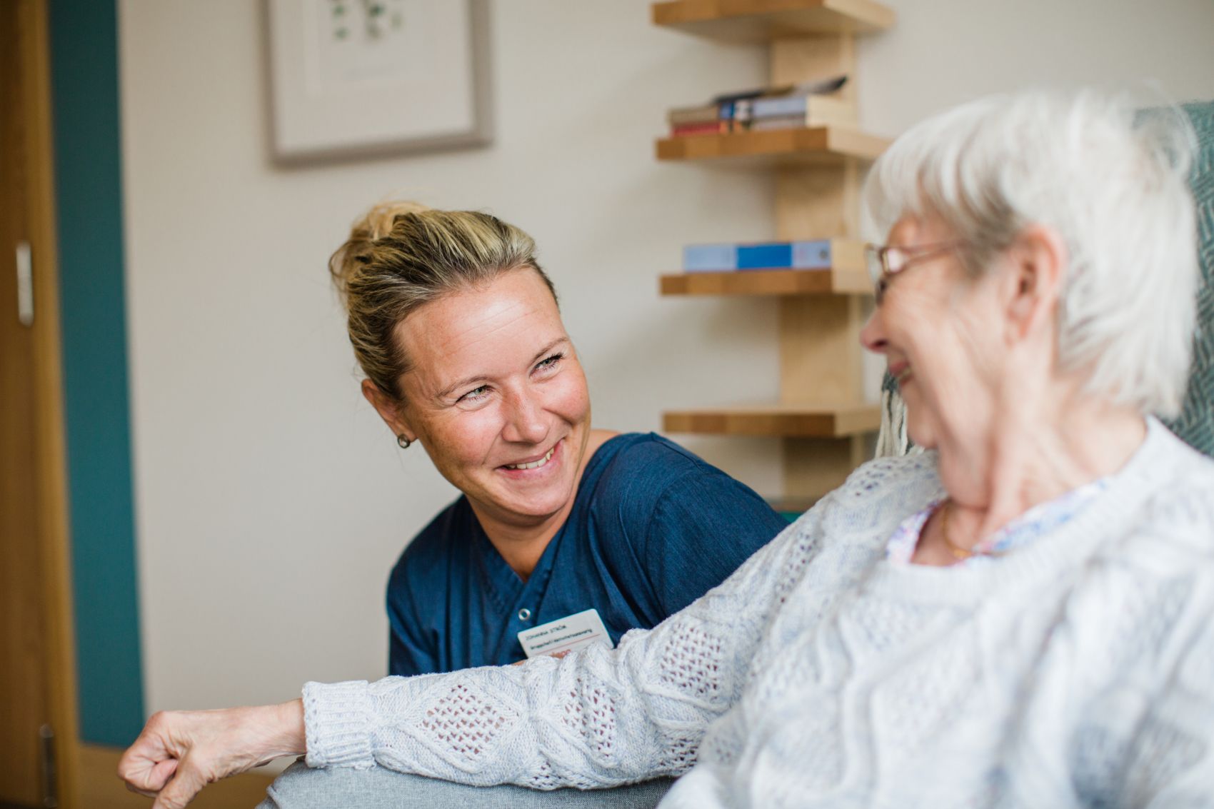 En helsemedarbeider og en eldre kvinne ler og koser seg på Kantarellen Bo- og rehabiliteringssenter.