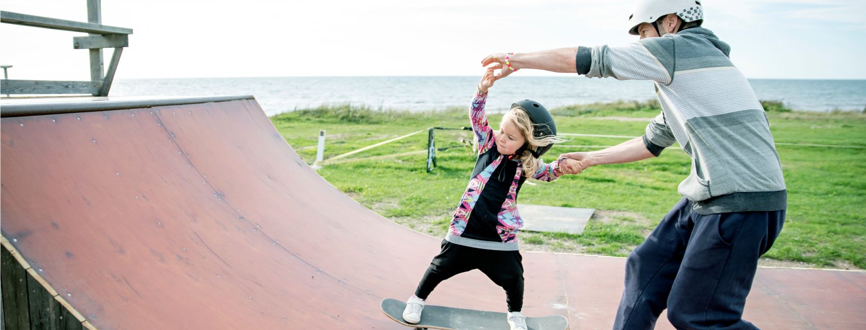 Fosterfar lærer fosterbarnet sitt, en liten jente å stå på skateboard