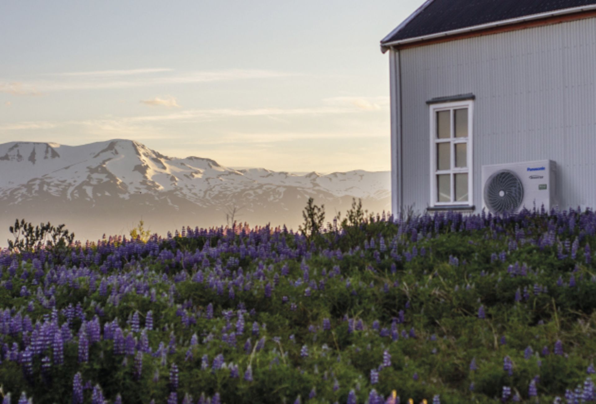 et hus med vakker utsikt til fjellene, og en panasonic varmepumpe på veggen
