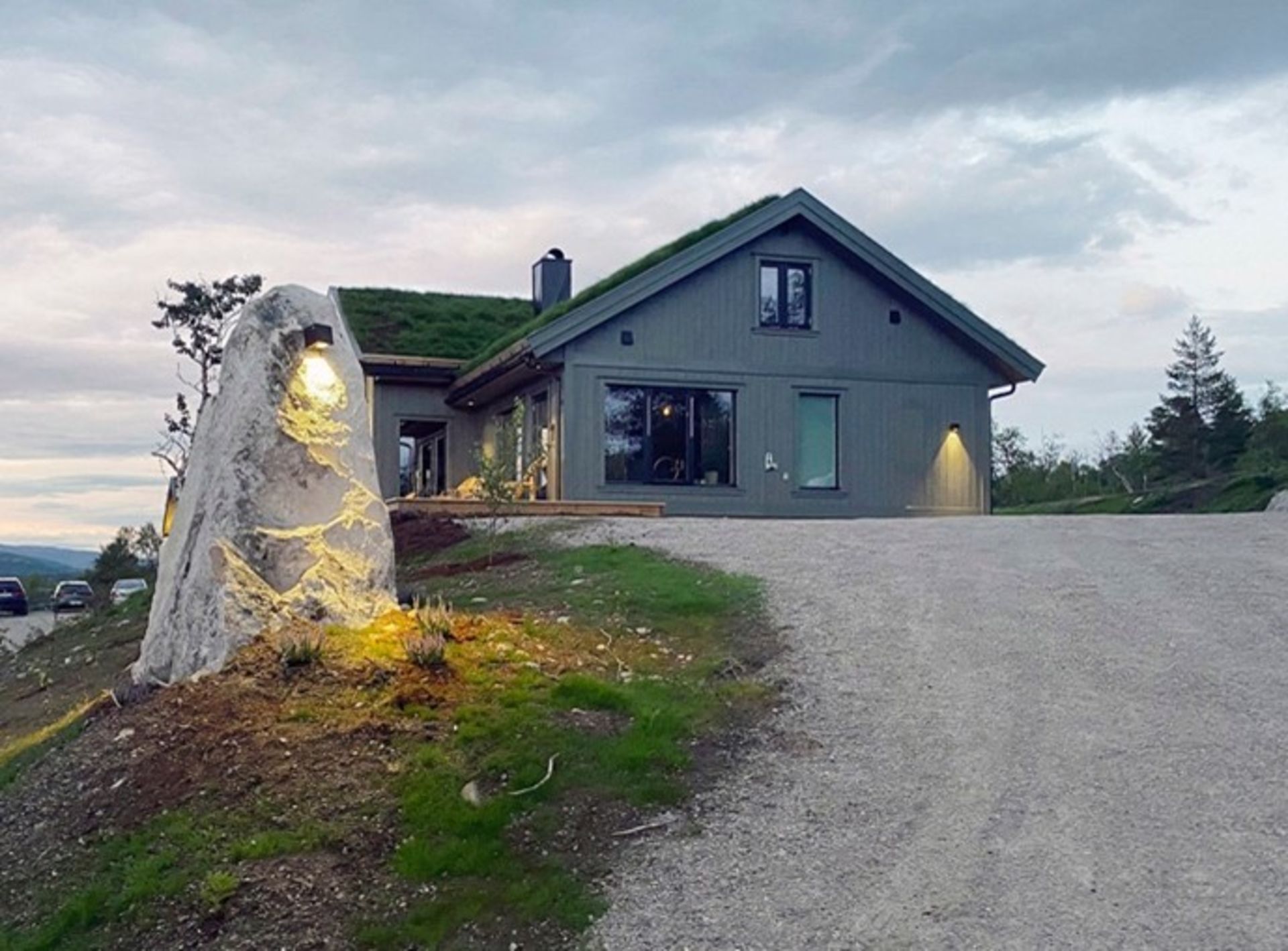 Oppkjørselen til en storslått hytte med varme lys brukt som dekor på stein. 