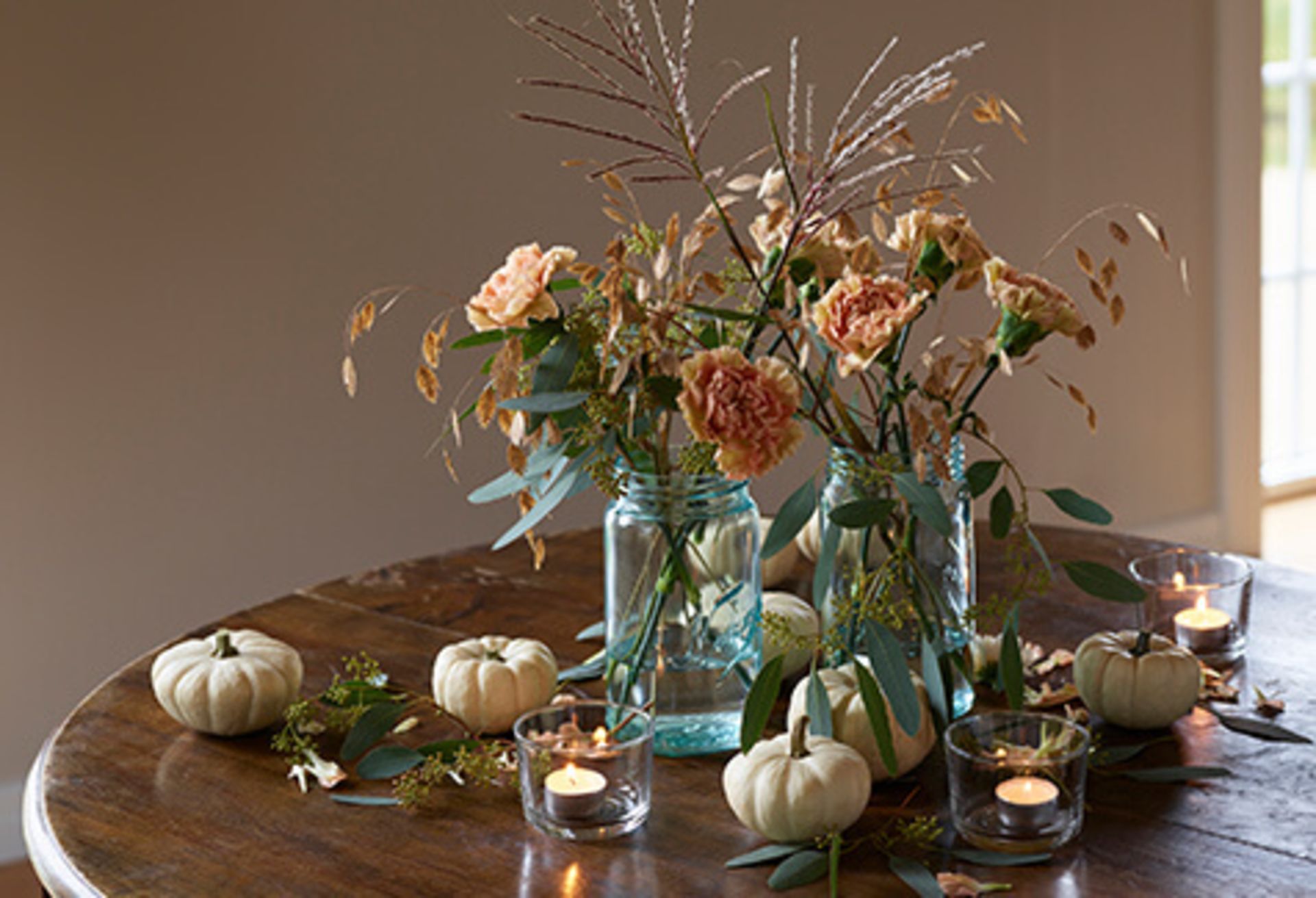 Bord til halloween pyntet med lyse gresskar og høstblomster