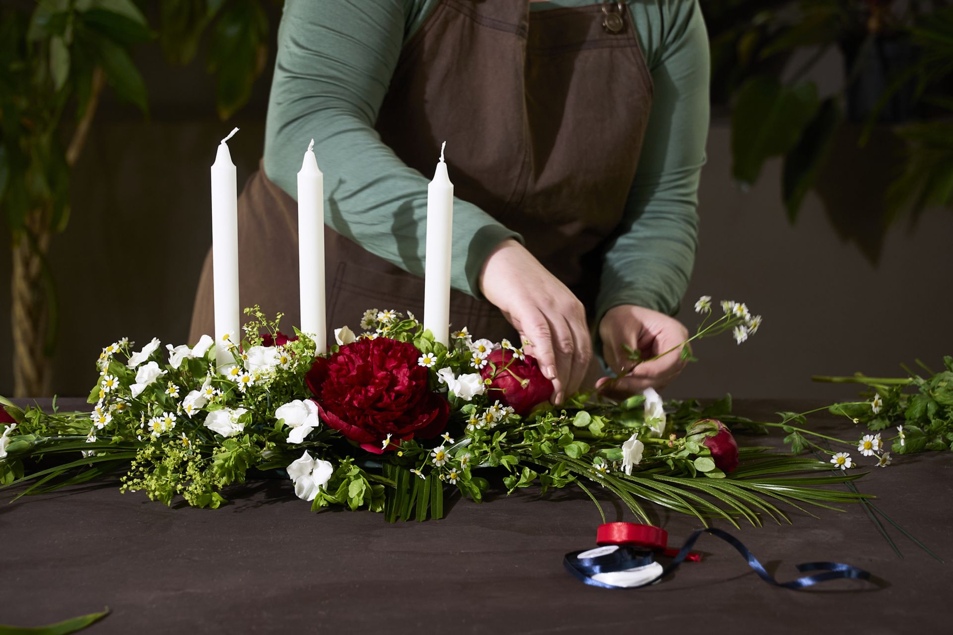 Hvite blomster stikkes inn i borddekorasjonens kjerne, en avlang oasis eller tabledeco