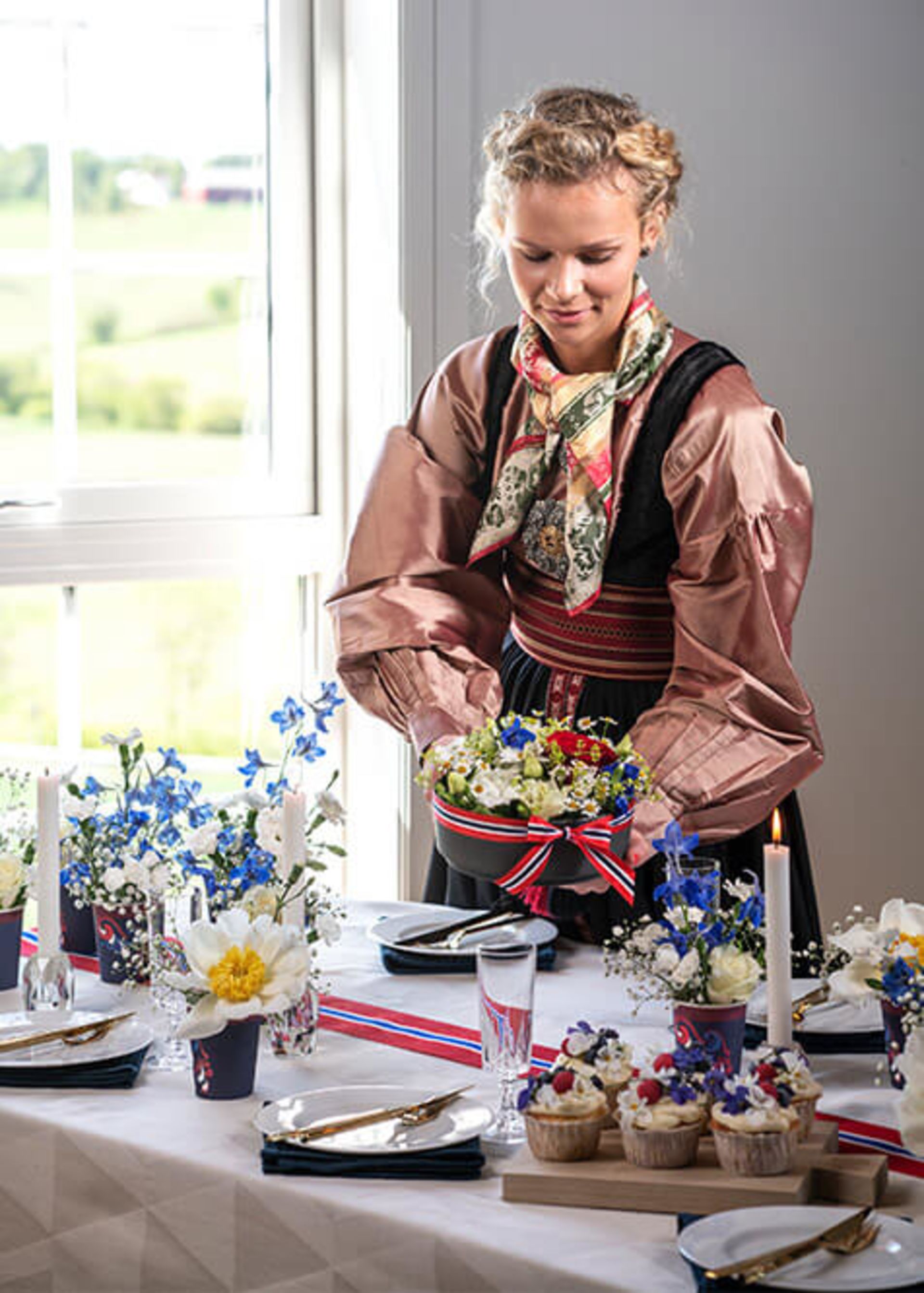 Kvinne i festdrakt pynter bordet på 17. mai