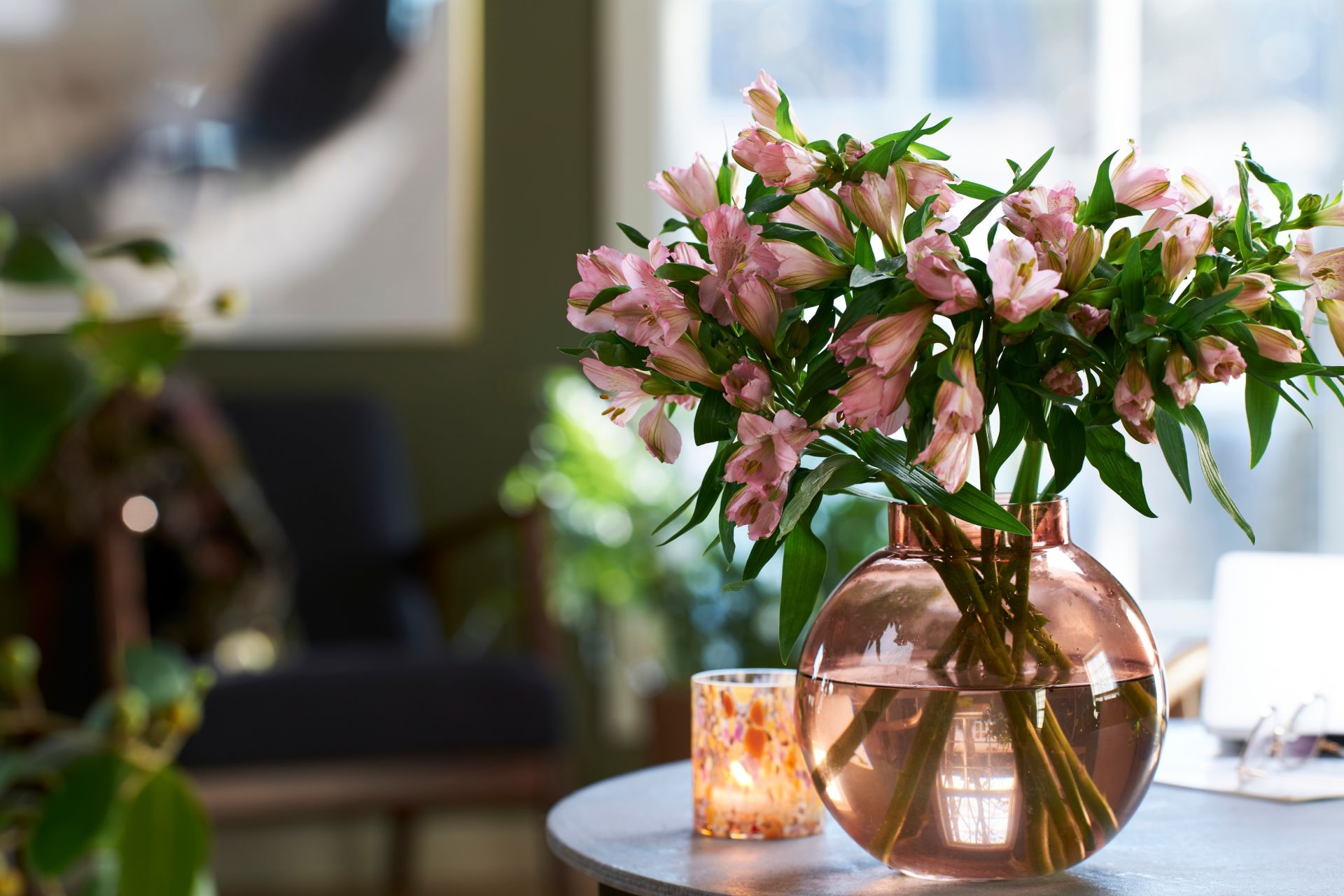 En vakker bukett med rosa alstromeria fra Interflora og tente lys på bordet