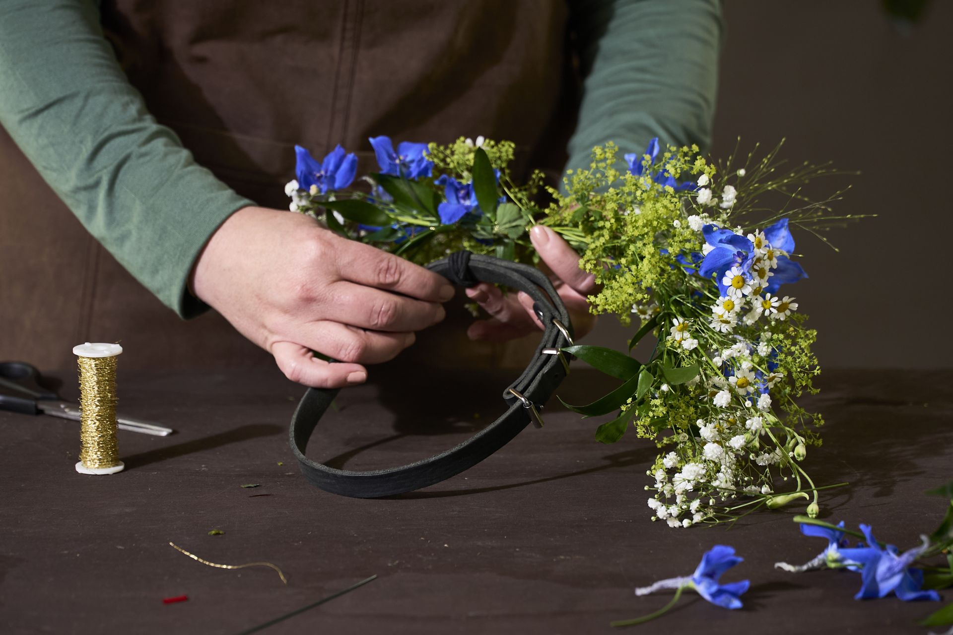 En blomsterdekoratør som lager en flott blomsterkrans til 17. mai