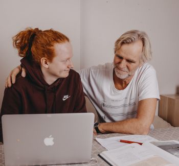 Fostersønn og fosterfar sitter og gjør lekser sammen på PC.