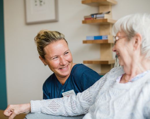 En sykepleier i Stendi snakker med en av en eldre dame ved et av våre sykehjem.