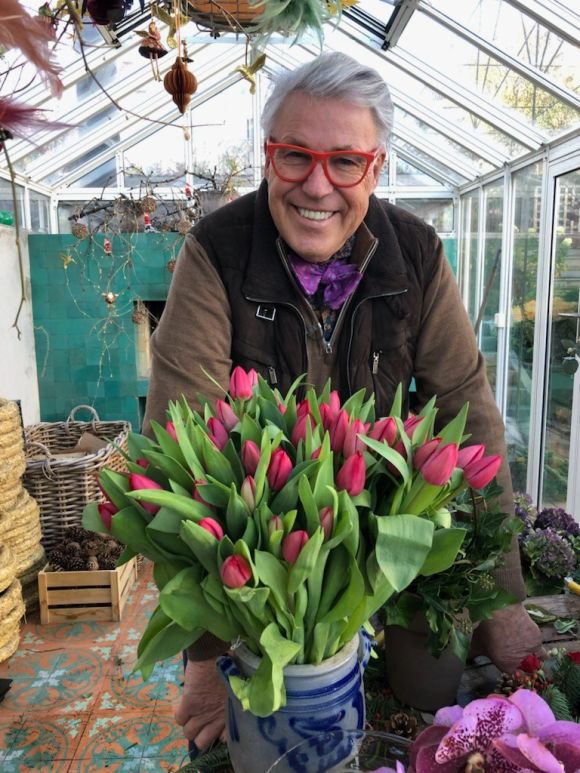 Finn Schjøll sammen med en stor bukett med tulipaner i et drivhus