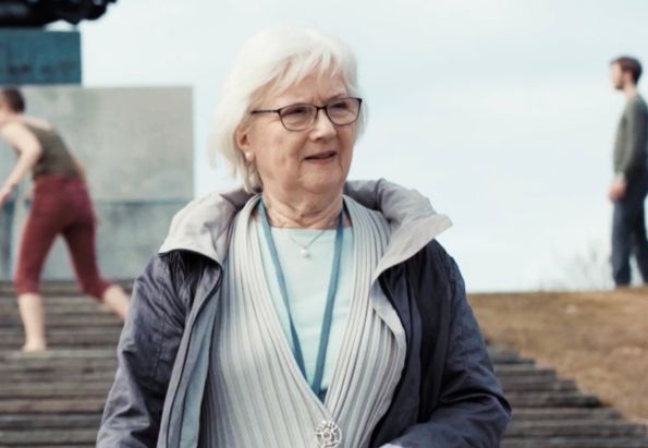 En eldre kvinne på gåtur i Vigelandsparken. Rundt halsen bærer hun en trygghetsalarm, fra Stendi.