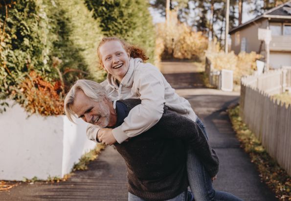 Fosterfar løfter fostersønn opp på ryggen.