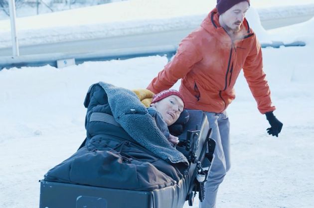 Assistent fra Stendi hjelper en mann som ligger i en rullestol, ute i snøen.
