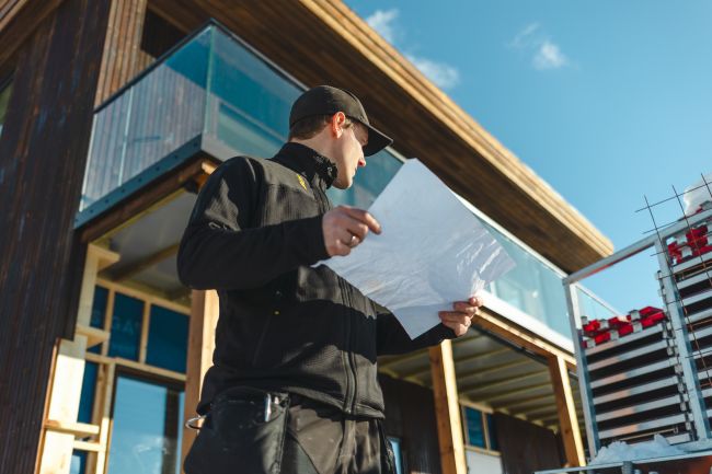 Magnus smiler til kameraet ute sammen med to kollegaer, foran en varebil