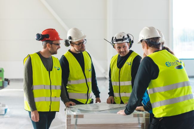 4 elektrikere står rundt et bord med plantegninger og snakker sammen