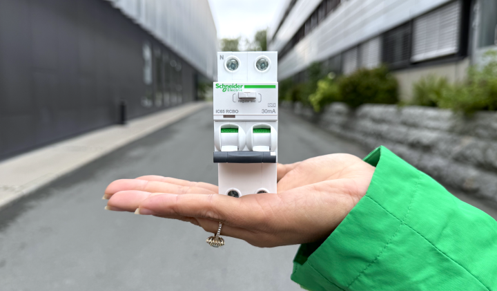 En jordfeilautomat fra Schneider presentert i en hånd.