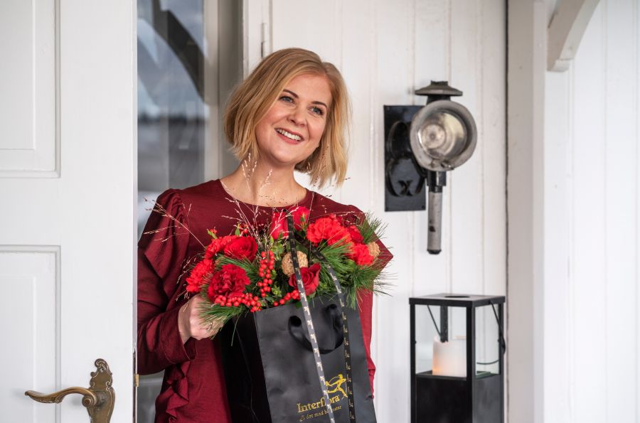 en kvinne som smiler med en blomsterbukett i hånda