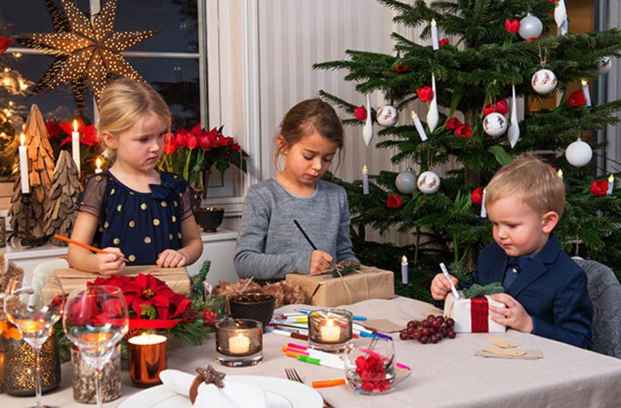 Tre barn som har juleverksted ved et juletre