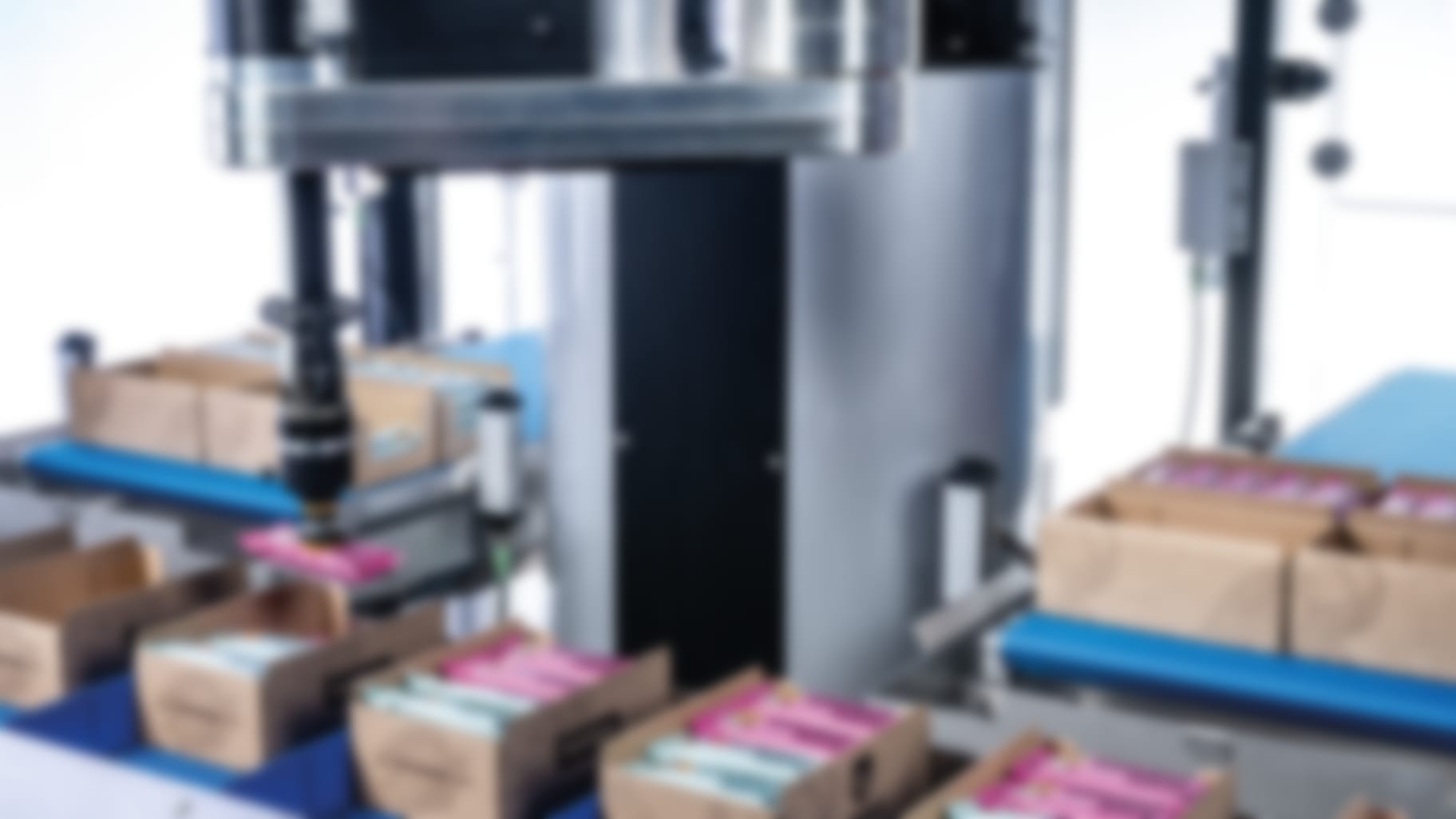 The cobot acts as a robotic arm, picking up pink-wrapped bars for packaging.