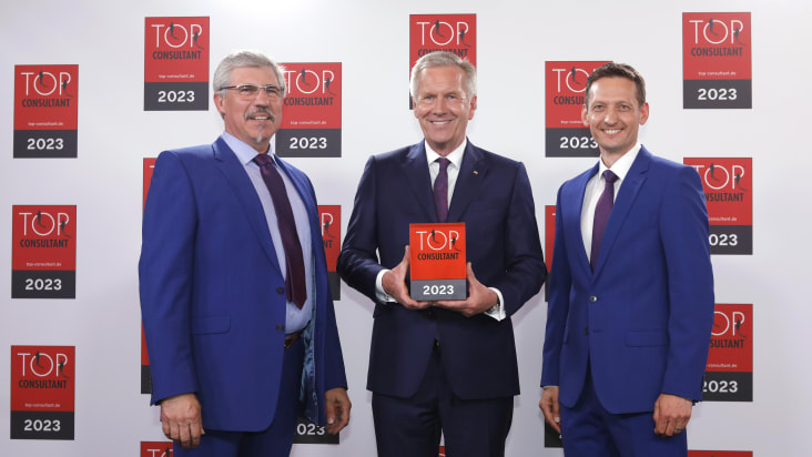 Michael Graf (left) and Heiko Burkhardt (right) from Schubert-Consulting receive the Top Consultant award from former German President Christian Wulff (centre).