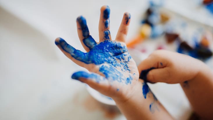 Kinderhand mit blauer Farbe beschmiert