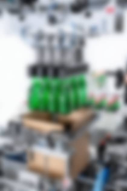 A robot lifts twelve green plastic bottles into a box