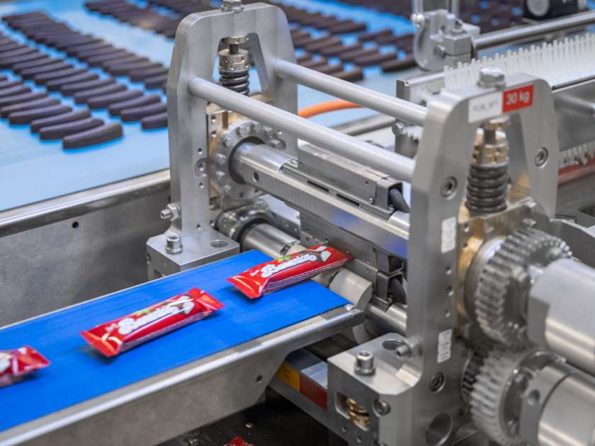 Red flowpacks labeled “Bananica” on a conveyor belt.