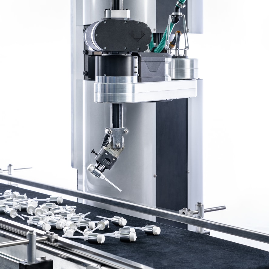 The Schubert cobot picks up a part of a cosmetics pump bottle from a group of unsorted products on the conveyor belt.