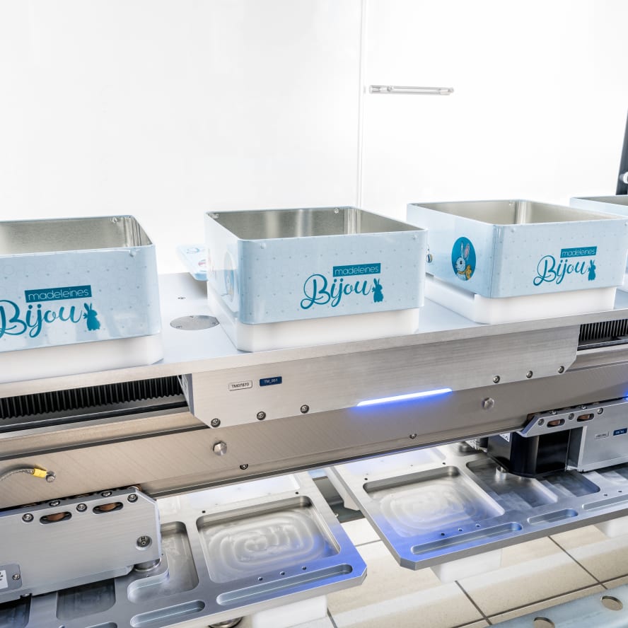 The Transmodul transport robot moves biscuit tins in a packaging machine to the filling station. 