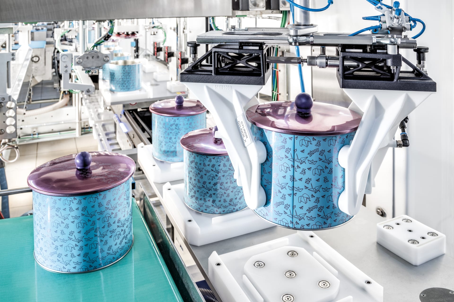 Ein Verpackungsroboter greift mit individuellen Werkzeugen aus dem 3D-Drucker eine runde Keksdose und setzt sie in ein weiteres 3D-Formatteil auf dem Transmodul.