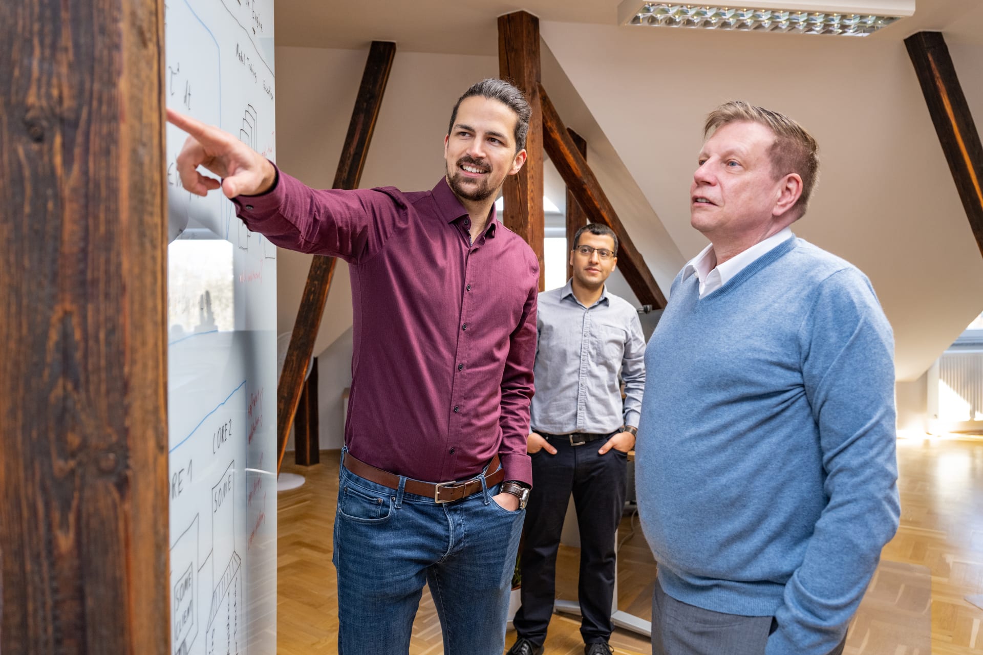 Geschäftsführer Ralf Schubert und Mitarbeiter von Schubert Motion besprechen Arbeitsergebnisse am Whiteboard.