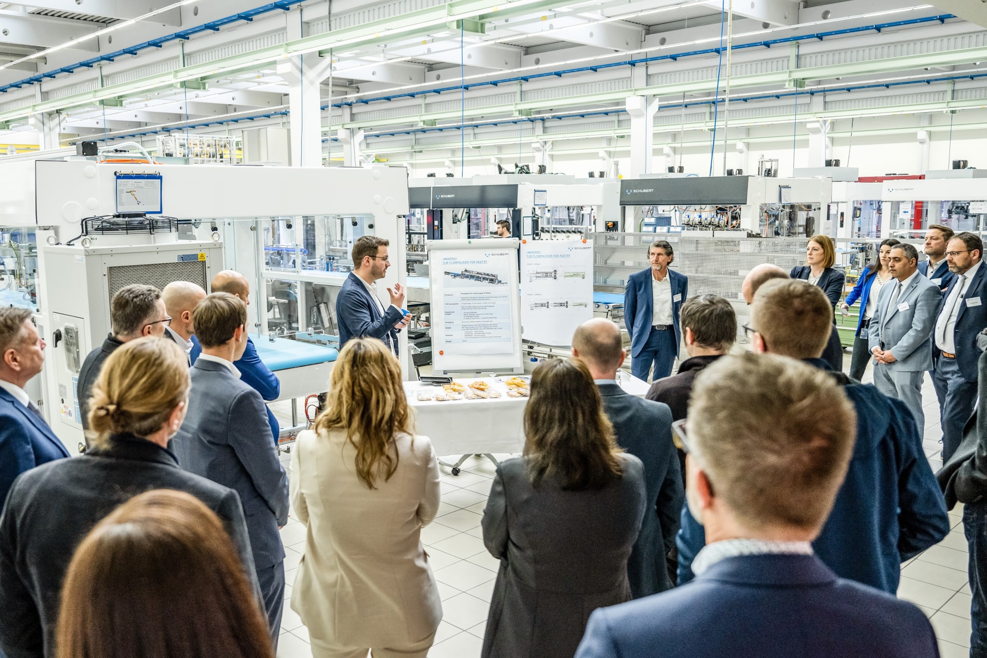 The participants of the Sales Meeting 2023 are trained in a hall in front of Schubert packaging machines