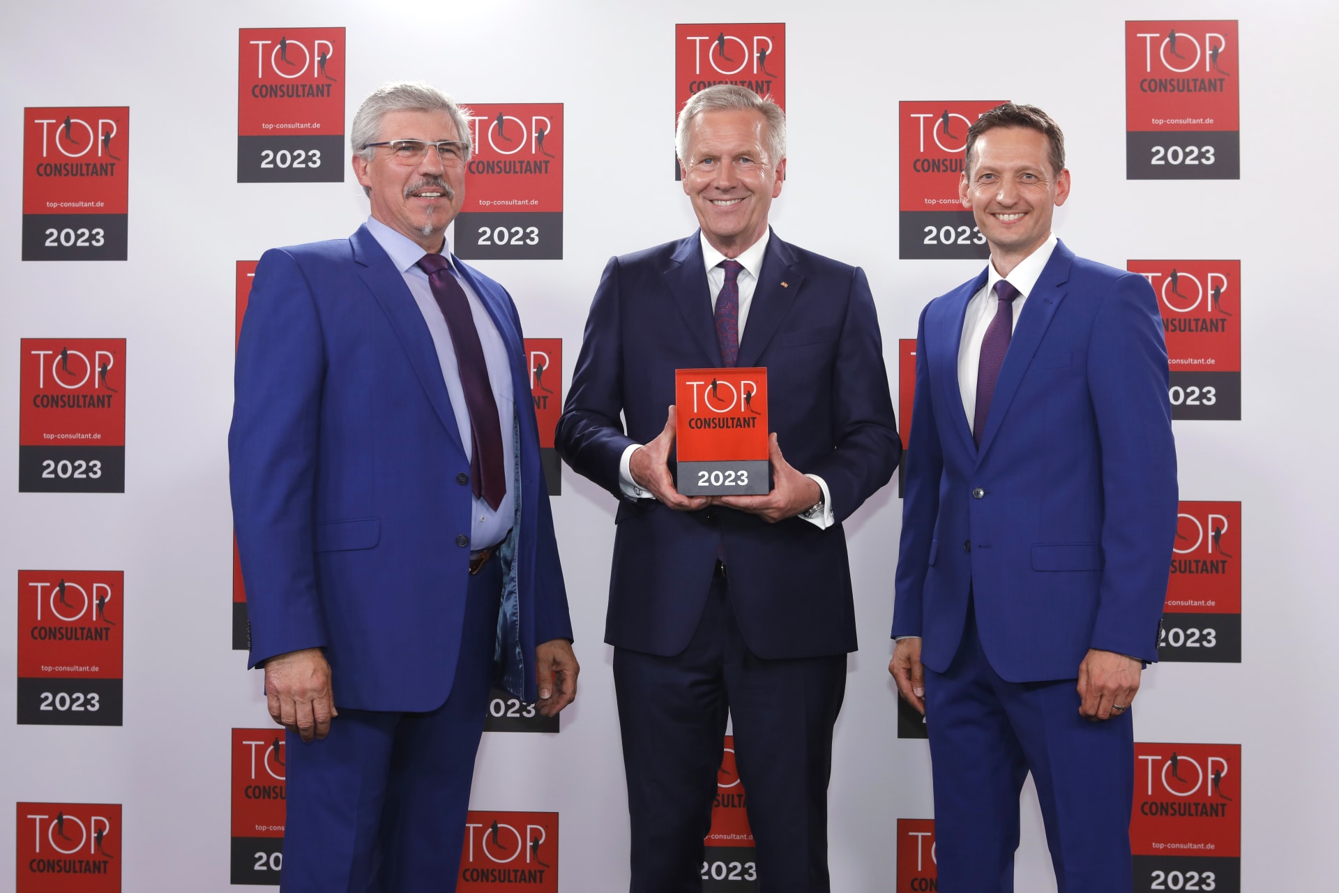 Michael Graf (left) and Heiko Burkhardt (right) from Schubert-Consulting receive the Top Consultant award from former German President Christian Wulff (centre).