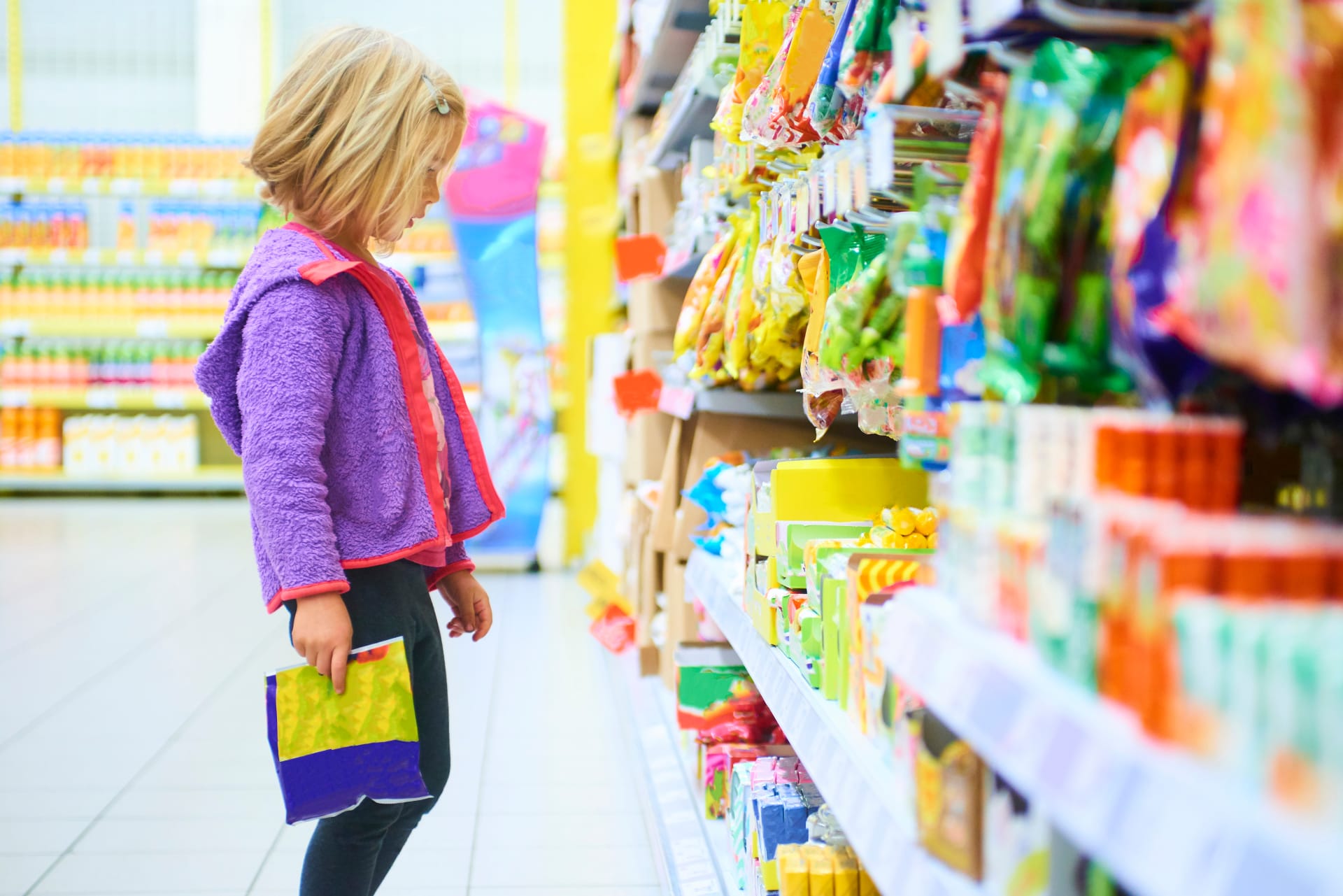 Girl stands fascinated in front of colourful sweets shelf