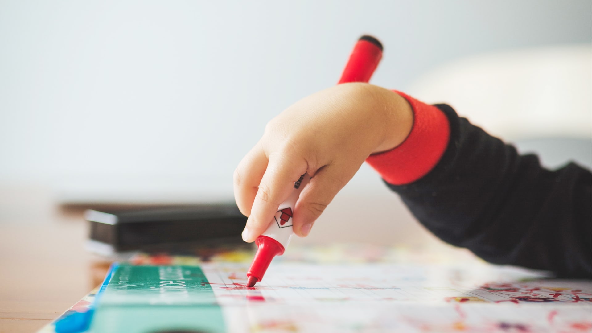 A child draws with red felt-tip pen