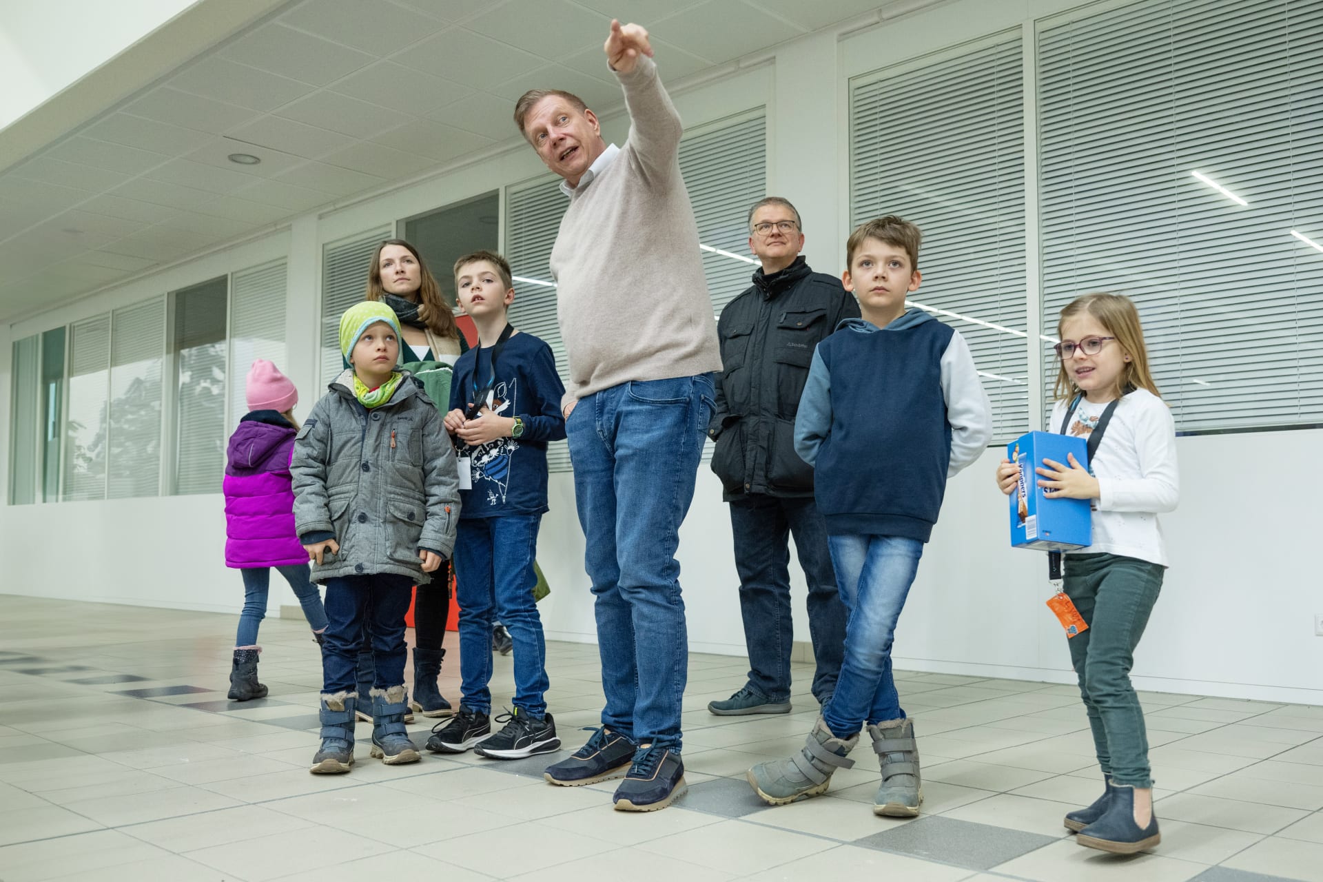 Ralf Schubert steht in der Gruppe von Kindern mit Begleitpersonen und zeigt auf etwas, das außerhalb des Bildes liegt. 