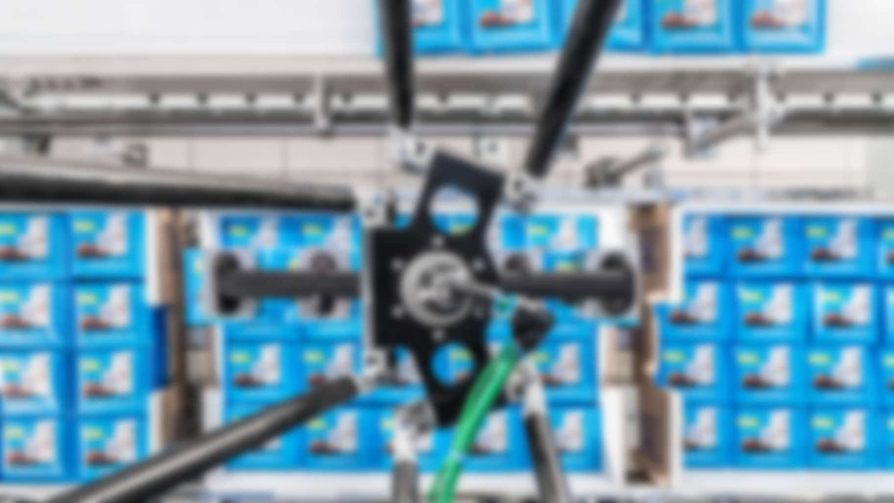 A robot places individual bars from transport cartons onto a feeding conveyor belt.