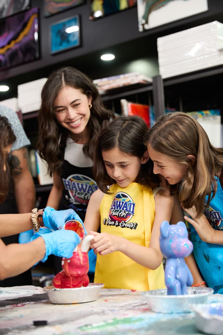 Mom and daughters pouring paint over fluid art figurine bears at ATL Fluid Art in Brookhaven, Atlanta