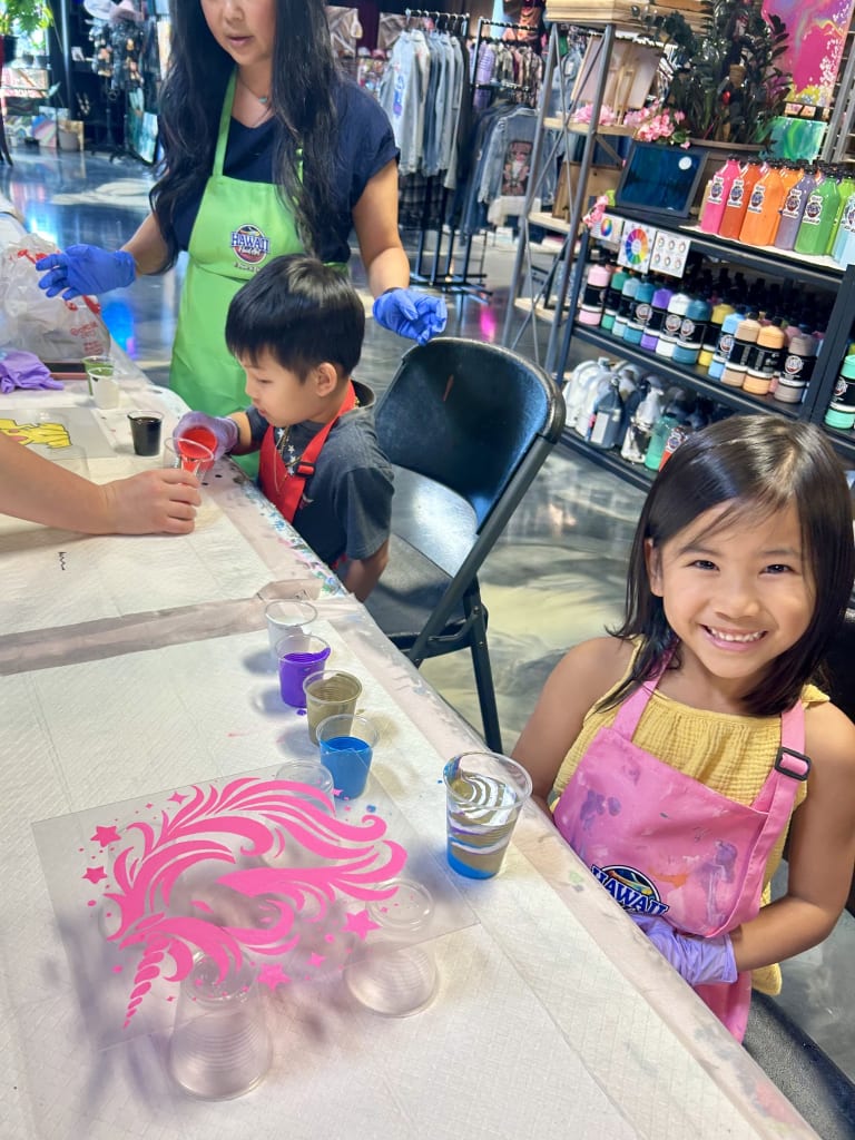 Children choosing paint colors with an instructor at a kids art camp table at ATL Fluid Art in Brookhaven, Atlanta