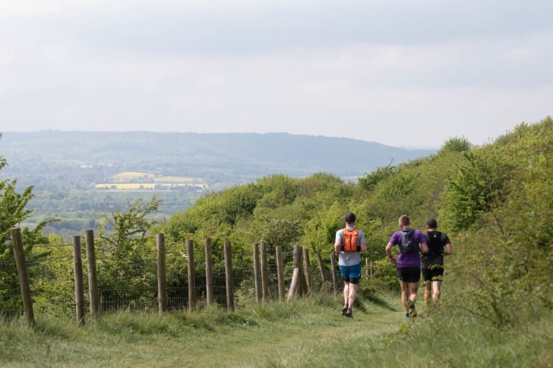 Runners on a chalk ridge path in the Chiltern Hills with views across the valley