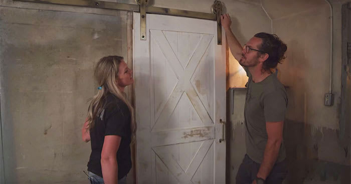 Two people checking a white sliding barn door with X details
